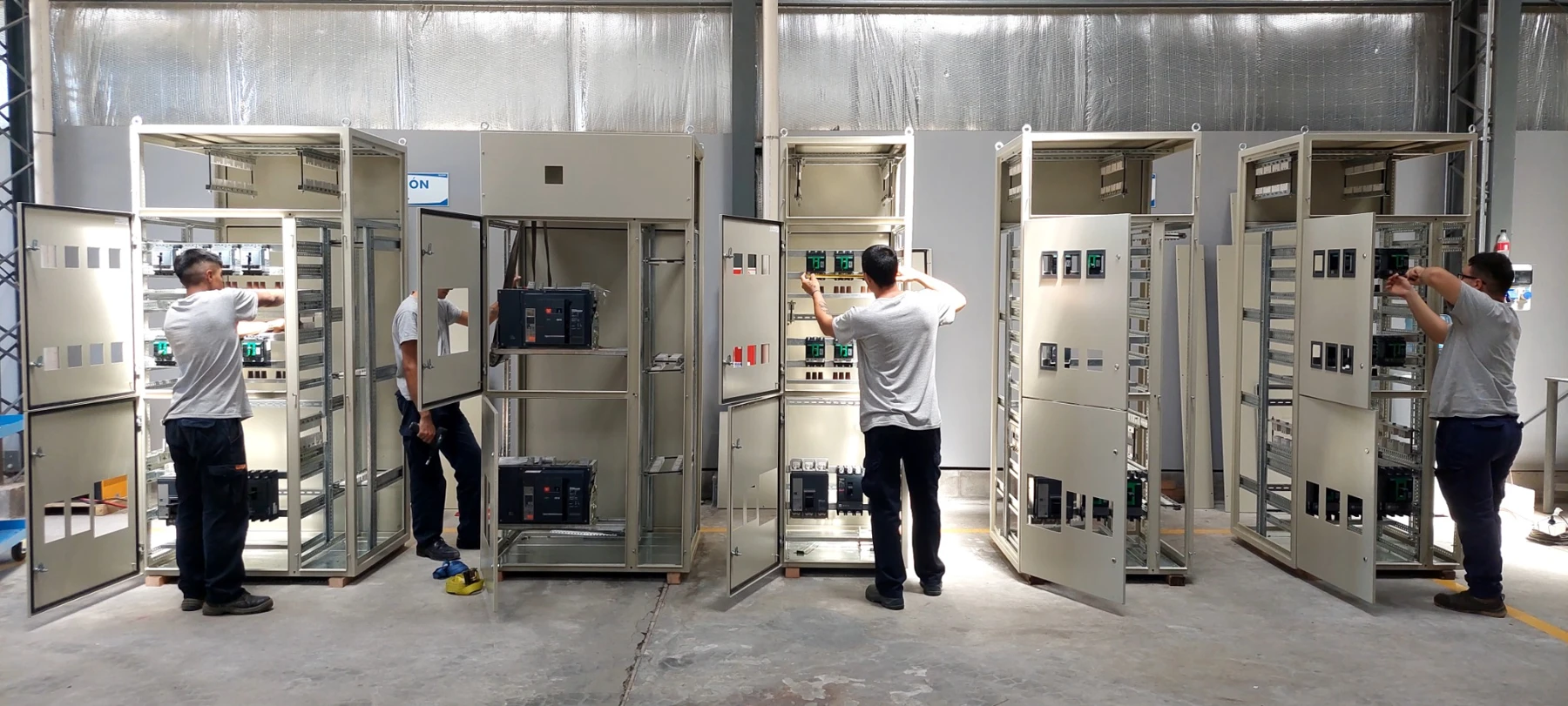 Personal de SILICOM trabajando en varios tableros eléctricos dentro del taller